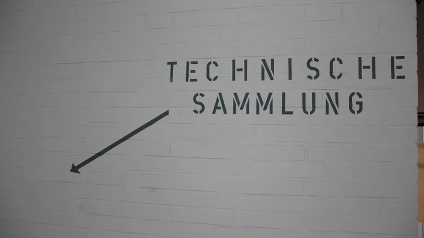 Richtungshinweis auf der Wand zur Technischen Sammlung mit Pfeil nach unten