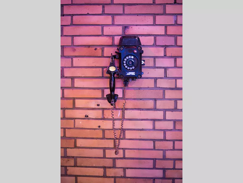Ein altes Telefon mit Wählscheibe an einer Backsteinmauer