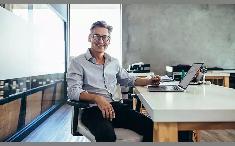 Mann sitzt am Schreibtisch und arbeitet am Laptop