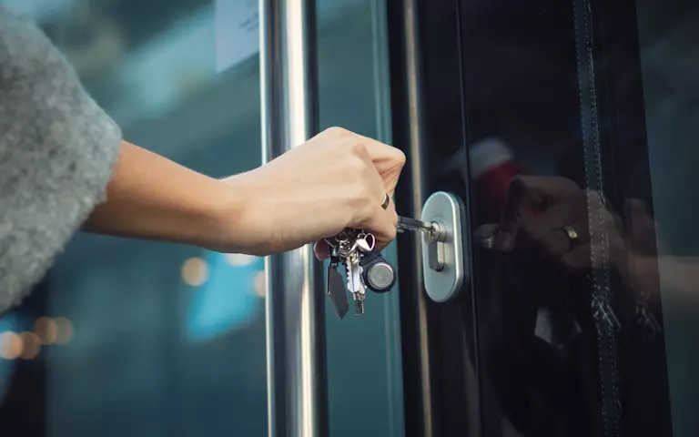 Hand schließt eine Glastür auf