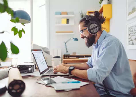 Mann mit Kopfhörern arbeitet an einem Laptop