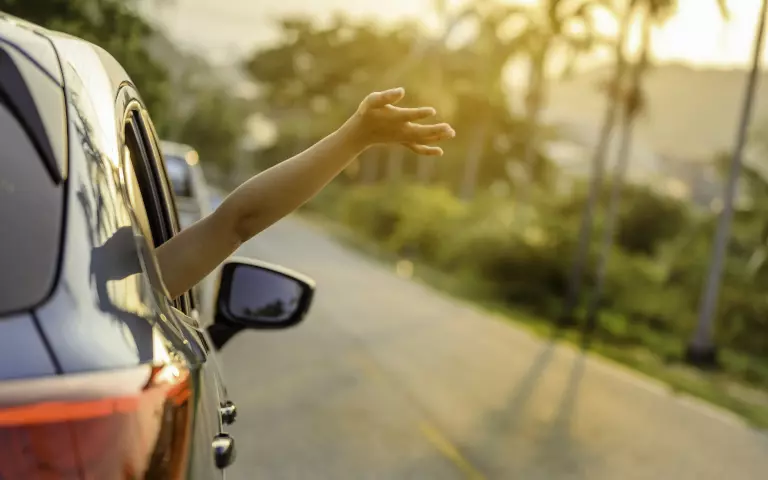 Person streckt einen Arm aus dem offenen Autofenster