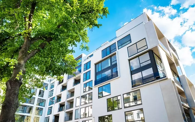 Modernes Wohngebäude mit Bäumen und blauem Himmel