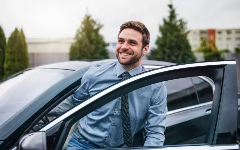 Mann im blauen Hemd steigt aus einem Auto aus