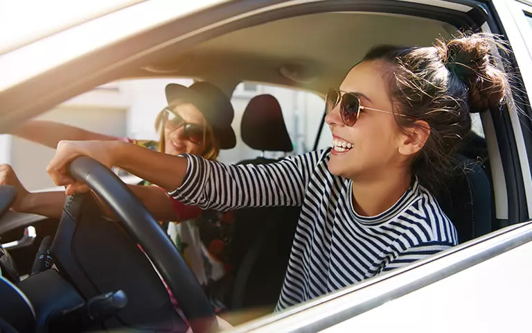 Lächelnde Frau sitzt hinter dem Steuer eines Autos