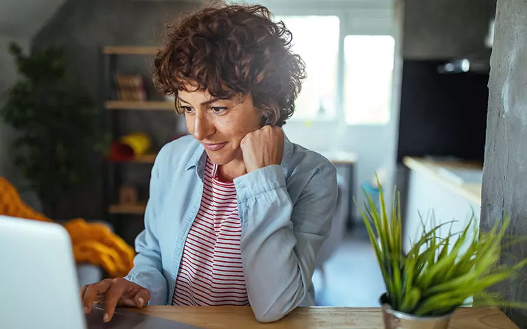 Frau mit dunklen Locken arbeitet an einem Laptop