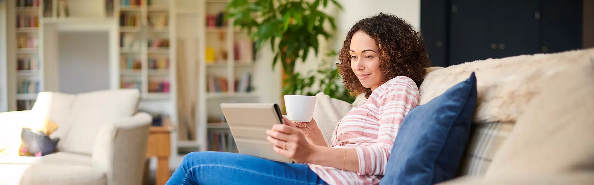 Frau sitzt auf dem Sofa und schaut auf ein Tablet