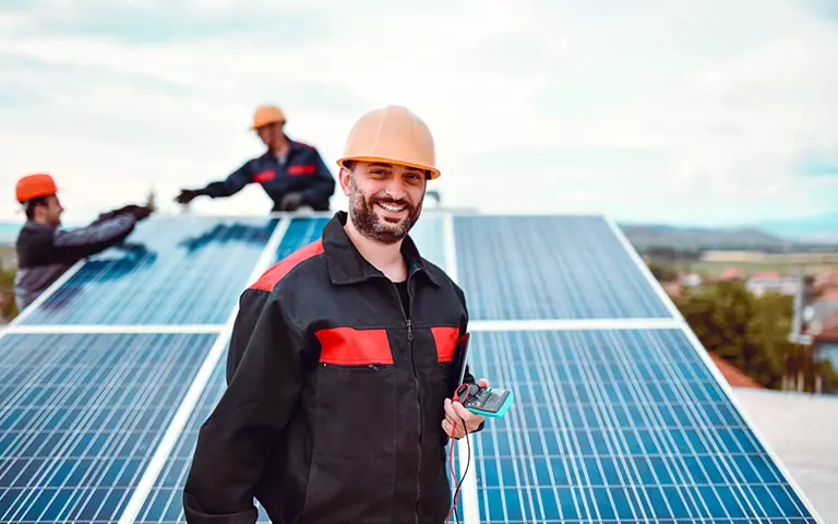 Techniker mit Messgerät vor einer Photovoltaik-Anlage